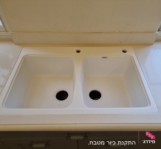 כיור כפול על משטח שיש בהיר במטבח